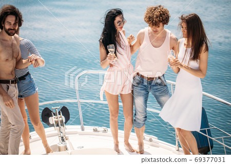 Marine cruise and vacation - youngsters with champagne glasses on boat or yacht 69377031