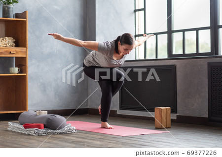 Young woman practicing yoga, standing in Eagle exercise, Garudasana pose Young woman practicing yoga, standing in Eagle exercise, Garudasana pose 69377226