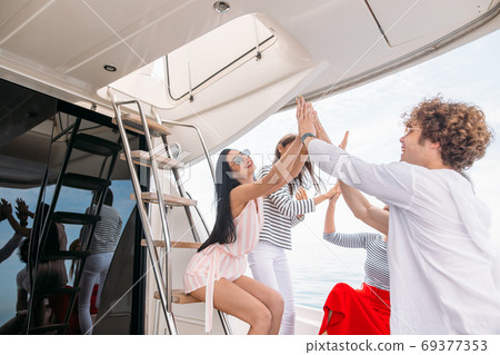 Group of friends making party on a yacht, having a fancy party on a luxury boat Group of friends making party on a yacht, having a fancy party on a luxury boat 69377353