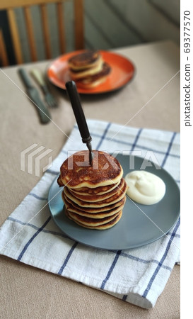 Plate with stack of homemade pancakes and sour cream on wooden table, selective focus 69377570