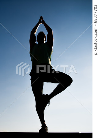 Athlete man silhouette posing outdoors on clear blue sky Athlete man silhouette posing outdoors on clear blue sky 69377702