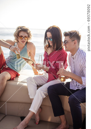 yacht drinking beers while talking Group of friends having party on sailing boat yacht drinking beers while talking Group of friends having party on sailing boat 69378092