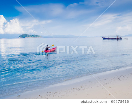 Man padding red kayak in blue sea at beauty day light, Travel plans in holidays or after retirement Man padding red kayak in blue sea at beauty day light, Travel plans in holidays or after retirement 69378416