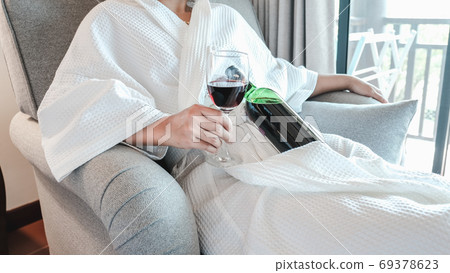 Woman hand holding a glass of wine and wine bottle on the sofa Woman hand holding a glass of wine and wine bottle on the sofa 69378623