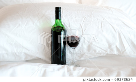 A glass of wine and wine bottle in the bed 69378624