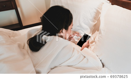 Young Woman hands holding smartphone in bed after wake up Young Woman hands holding smartphone in bed after wake up 69378625