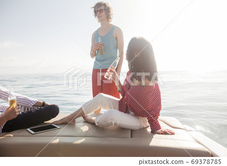 yacht drinking beers while talking Group of friends having party on sailing boat 69378785