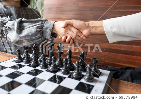 Business women shaking hands after play chess on board with white background 69378984