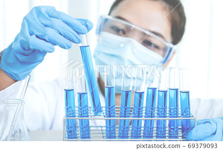 Scientists hold glass tube filled with blue chemical liquid for research and analysis in laboratory Scientists hold glass tube filled with blue chemical liquid for research and analysis in laboratory 69379093
