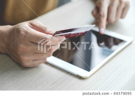 Businessman hand hold credit card to online shopping on computer tablet from home Businessman hand hold credit card to online shopping on computer tablet from home 69379095