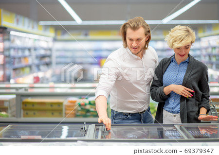 happy caucasian couple choosing frozen food at grocery store in shopping mall. 69379347