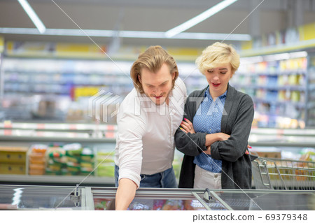 happy caucasian couple choosing frozen food at grocery store in shopping mall. 69379348