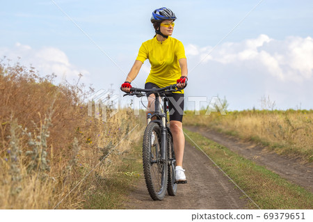 Beautiful girl in yellow riding a bike in nature. Sports and rec 69379651