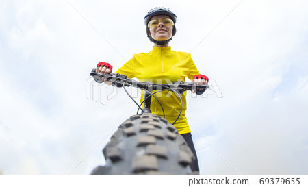 Beautiful girl cyclist looking forward to the wheel of the bike. Beautiful girl cyclist looking forward to the wheel of the bike. 69379655