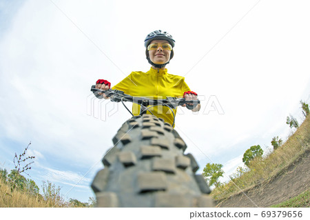 Beautiful girl in yellow riding a bike on the path in the field. Beautiful girl in yellow riding a bike on the path in the field. 69379656