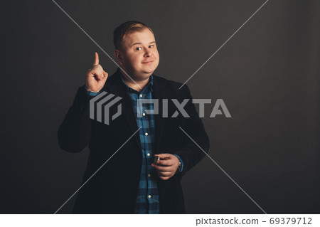 overweight young man pointing up overweight young man pointing up 69379712