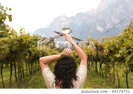 Young woman with a glass of white wine in the vineyards of Italy. Person pouring wine. Free space Young woman with a glass of white wine in the vineyards of Italy. Person pouring wine. Free space 69379732
