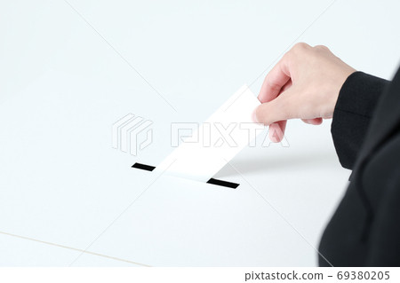 A close-up of a woman in a suit putting paper in an election ballot box 69380205