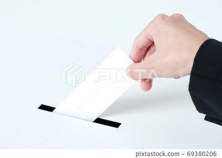 A close-up of a woman in a suit putting paper in an election ballot box 69380206