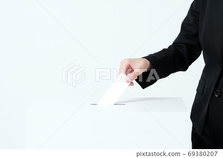 A woman in a suit putting paper in an election ballot box 69380207
