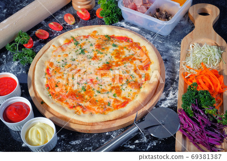 Salmon Seafood Pizza on a Black table with ingredients around Salmon Seafood Pizza on a Black table with ingredients around 69381387