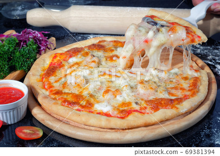 Seafood Pizza on a Black table with ingredients around Seafood Pizza on a Black table with ingredients around 69381394