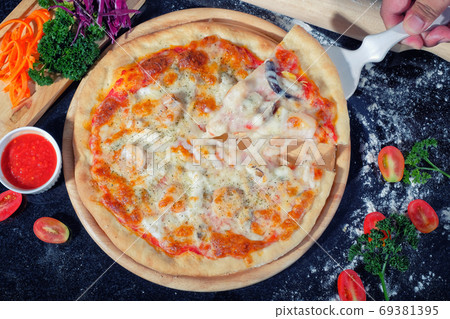 Seafood Pizza on a Black table with ingredients around Seafood Pizza on a Black table with ingredients around 69381395