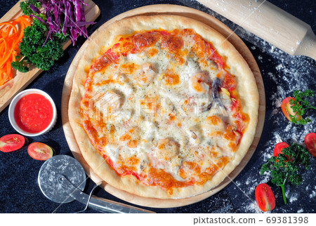 Seafood Pizza on a Black table with ingredients around Seafood Pizza on a Black table with ingredients around 69381398