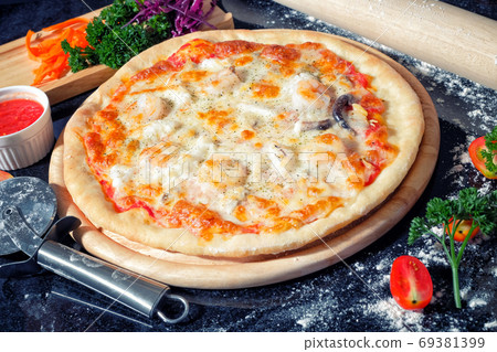 Seafood Pizza on a Black table with ingredients around Seafood Pizza on a Black table with ingredients around 69381399