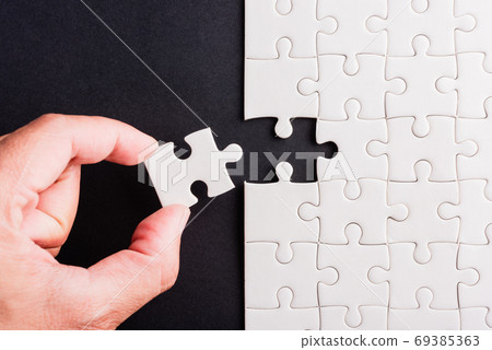 hand-holding last piece white paper jigsaw puzzle game last piec hand-holding last piece white paper jigsaw puzzle game last piec 69385363