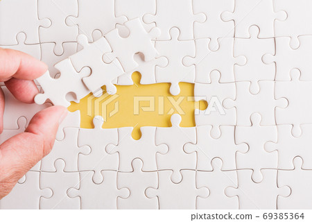 hand-holding last piece white paper jigsaw puzzle game last piec hand-holding last piece white paper jigsaw puzzle game last piec 69385364