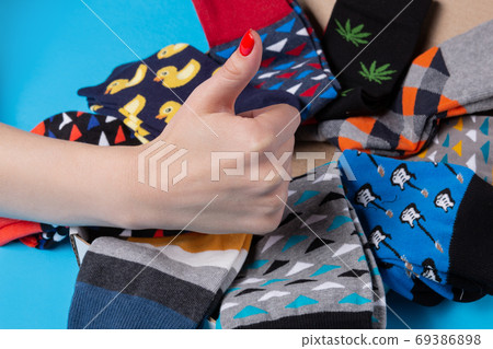 many colored socks laid out in a circle, female hand shows a gesture of approval, concept 69386898