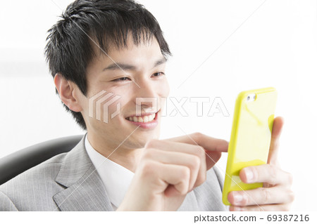 A businessman looking at a smartphone 69387216