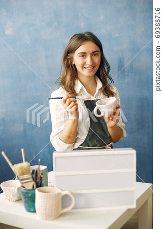 A young woman mpainting dishes in a pottery 69388716