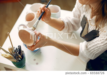 A young woman mpainting dishes in a pottery 69388726