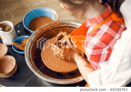 People making a vaze from a clay on a pottery's machine 69388761