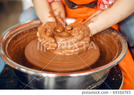 People making a vaze from a clay on a pottery's machine 69388765