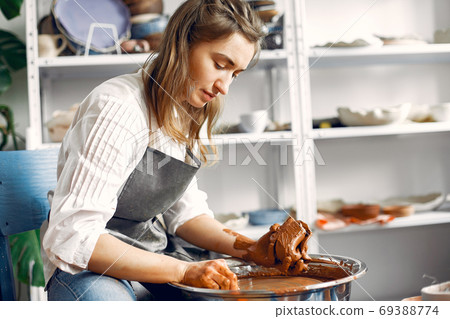 Girl making a vaze from a clay on a pottery's machine Girl making a vaze from a clay on a pottery's machine 69388774