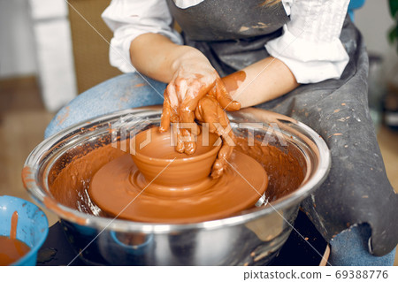 Girl making a vaze from a clay on a pottery's machine 69388776