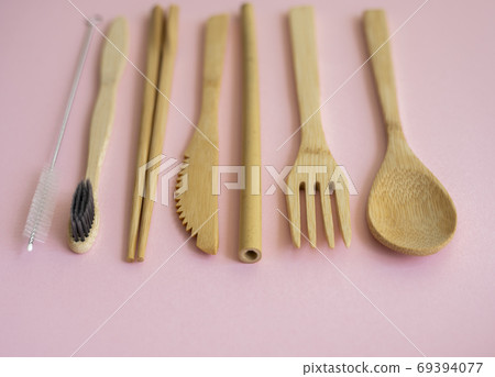 Eco friendly bamboo cutlery set in a case on a pink background. Zero waste concept. Set of bamboo cutlery in a case on a laying on a table. Spoon, fork, knife, toothbrush, tube and chinese sticks. 69394077
