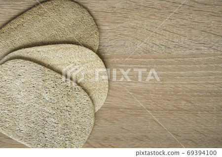Natural loofah kitchen dish washing sponges. Eco friendly dishwashing sponge on a table, top view. Biodegradable dishwashing scrub pad. Natural loofah kitchen dish washing sponges. Eco friendly dishwashing sponge on a table, top view. Biodegradable dishwashing scrub pad. 69394100