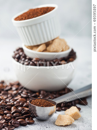 Three bowls on top of each other with fresh raw coffee beans and powder with cane sugar on light  69395897