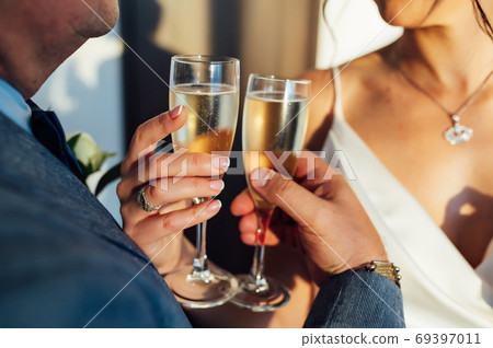 Bride and groom hold in their hands glasses with wine Bride and groom hold in their hands glasses with wine 69397011