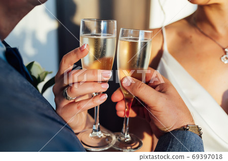 Bride and groom hold in their hands glasses with wine Bride and groom hold in their hands glasses with wine 69397018
