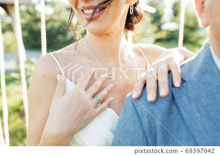 Close-up portrait of a bride and groom standing on the city street and lovely hugging Close-up portrait of a bride and groom standing on the city street and lovely hugging 69397042
