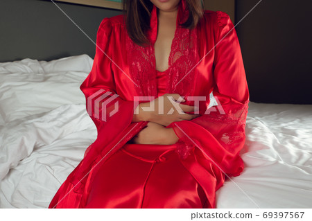 Irritable Bowel Syndrome or IBS. Asian woman in a silk nightgown Irritable Bowel Syndrome or IBS. Asian woman in a silk nightgown 69397567