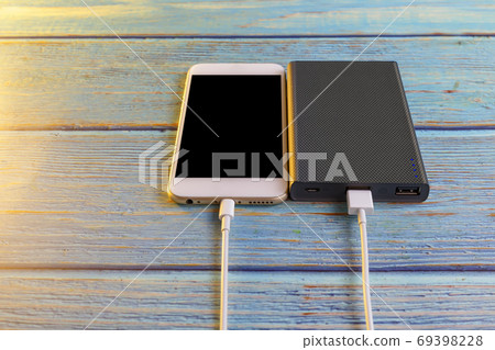Close up smartphone charging with power bank on blue background Close up smartphone charging with power bank on blue background 69398228