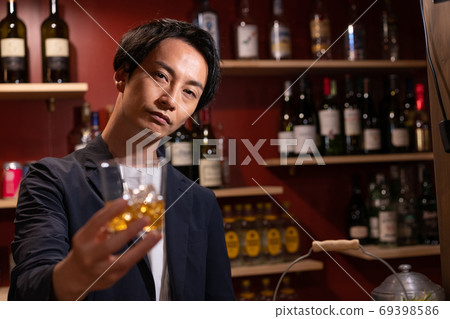 Young bartender serving whiskey Young bartender serving whiskey 69398586