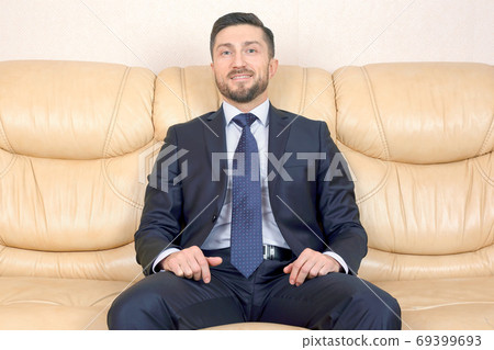successful business man sitting on a leather couch successful business man sitting on a leather couch 69399693