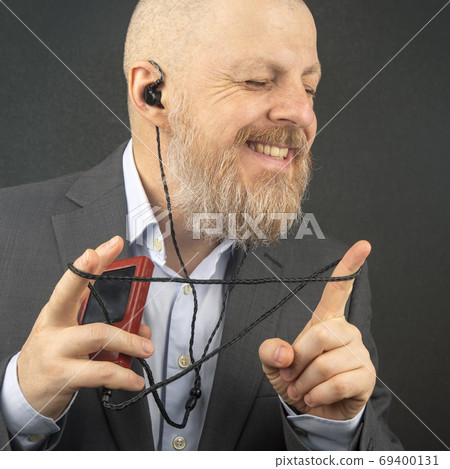 bearded business man enjoys listening to his favorite music from 69400131